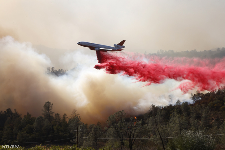 Repülőgépről ledobott tűzgátló anyaggal próbálják megfékezni a lángokat a kaliforniai Deer Park település közelében pusztító erdőtűz helyszínén 2020. szeptember 27-én.
