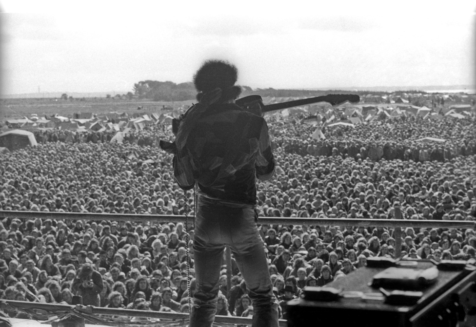 Jimi Hendrix az egyik legendás trükkjével a tömeg előtt. Neki tulajdonítják azt a találmányt, amikor a gitáros a fogaival szólózik a hangszerén. Hendrix ezen kívül még a háta mögött is szeretett játszani, illetve fel is gyújtotta a gitárját egy-egy extatikus pillanatában.