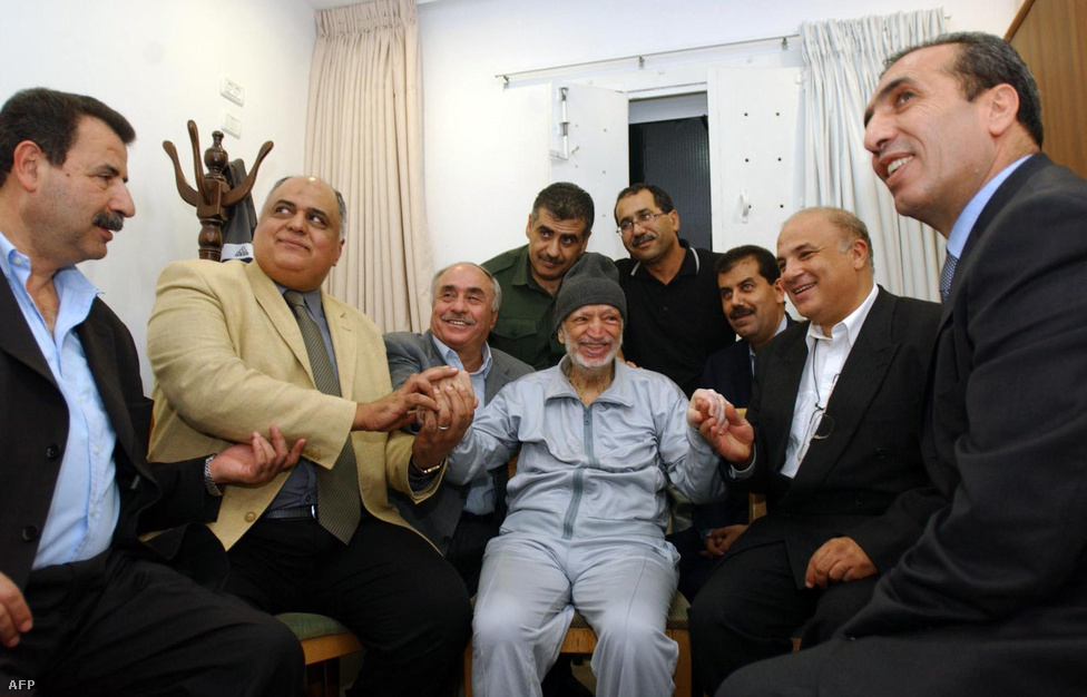  Arafat és támogatói a vezér ramallahi szállásán, ahol 20 hónapot kellett kényszerűségből eltöltenie fenyegetettsége miatt. Arafat, bár a képen bizalmasaival és testőreivel mosolyog, orvosai szerint itt betegedett meg végleg. Komoly influenzát és ritka vérkeringési rendellenességet állapítottak meg nála.