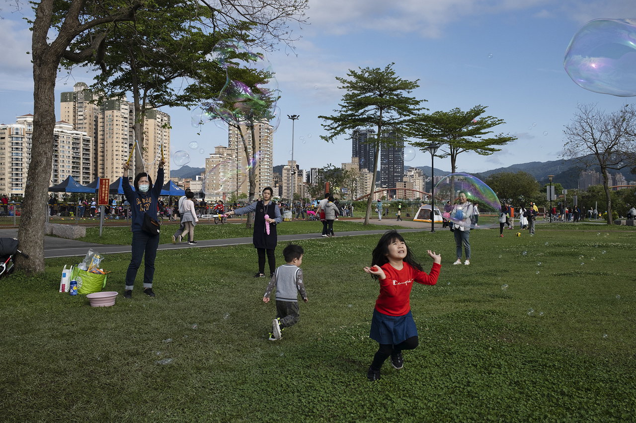 Gyerekek játszanak egy városi parkban, miközben a világban csúcsokat dönt az első hullám. Hszintien, 2020. március 29-én. 