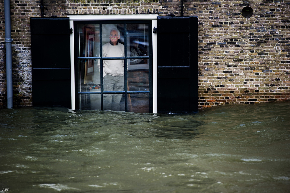 Egy férfi az elárasztott utcát figyeli ablakából Hollandiában. A 110 km/órás szél és a heves esőzések következében az utcákon hömpölygött a víz több holland tengerparti városban, mivel az ország negyede a tengerszint alatt fekszik. (Január 5.)