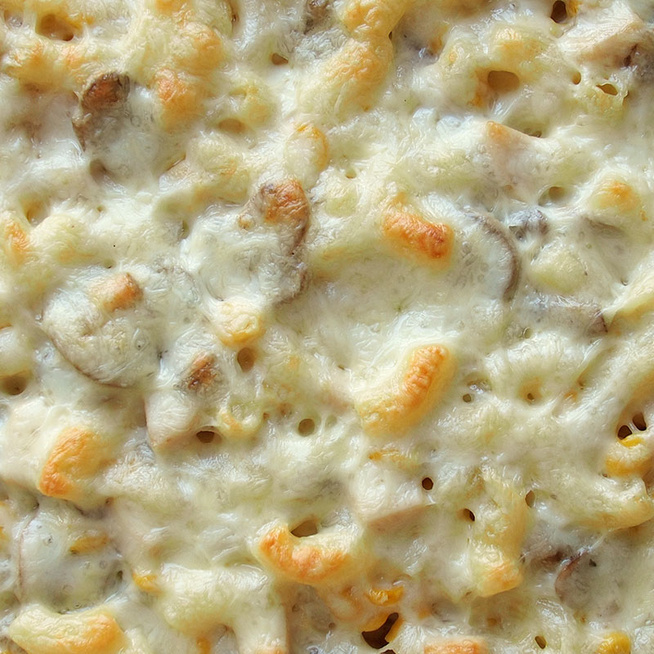Sütőben sült rakott tészta pirult, olvadt sajttal borítva: sonka, gomba és kukorica gazdagítja