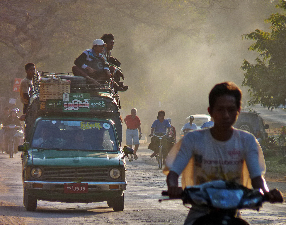 Jobbkormányos autóval az út jobb oldalán – megszokott, sőt, szabályos közlekedési alaphelyzet ez Burmában. Az utakon a „Jobbra tarts!” érvényes, ugyanakkor az autók nagy része Thaiföldről, Indiából, Japánból származó, agyonhasznált, olcsó jobbkormányos típus. A Bagan környékén készült képen együtt láthatjuk a közlekedés három tipikus eszközét, a biciklit, a robogót és a pickupot.