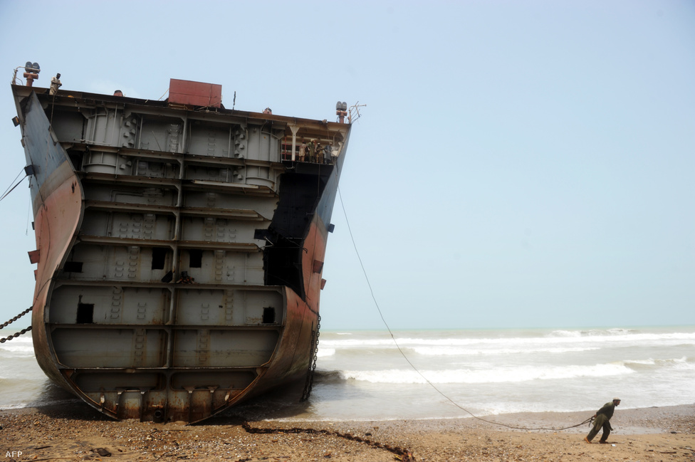 Hajóbontó munkás készül teherautójához láncolni egy partra vetett tankerhajó borításának egy darabját, hogy azt a jármű erejével le tudja választani a hajótestről a pakisztáni Geddani város tengerparjtán. 