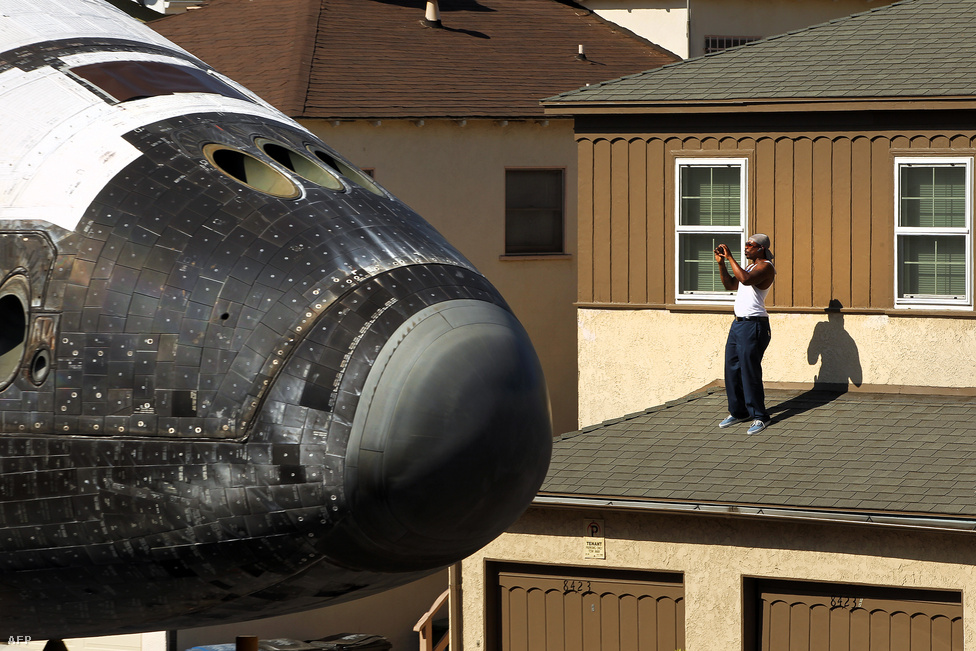 Háza tetejéről fotózza az Endeavour űrsiklót egy férfi Los Angelesben. Az utolsóként leszerelt űrrepülőt októberben speciális tréleren szállították át a városon, és a California Science Centerben állítják ki.