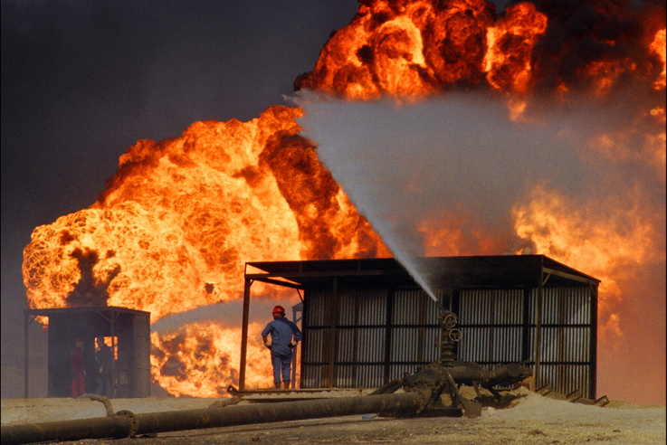 American Red Adair fire fighting worker sets up a permanent hose 30 May 1991 in Al-Ahmadi oil field in southern Kuwait in order to keep the fire of the damaged oil wells in the direction of the wind whilst protecting the employees who attempt to extinguish it. In 1991 Iraqi troops retreating after a seven-month occupation smashed and torched 727 wells badly polluting the atmosphere and creating crude oil lakes. In addition up to eight billion barrels of oil were split into the sea by Iraqi forces damaging marine life and coastal areas up to 400 kilometres (250 miles) away. Kuwait will seek more than 16 billion dollars compensation for environment destruction wrought by Iraq during the 1991 Gulf War Kuwaiti newspaper Al-Anba said 07 December 1998.