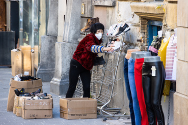 Egy cipőbolt tulajdonosa helyezi ki termékeit boltja előtt a budapesti Keleti Pályaudvarnál