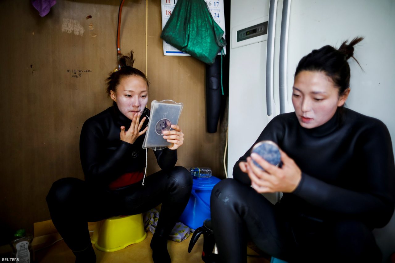 Dzsin és Vu környezetbarát napkrémmel kenik be az arcukat, mielőtt munkába mennek Kodzse szigetén 2021. március 31-én. Ők ketten a legfiatalabb henyók közé tartoznak. A legtöbb henyo már elmúlt 70 éves. Dzsin és Vu létrehoztak egy You Tube-csatornát, amelyen bemutatják a tengeri asszonyok életét. A legnépszerűbb videójukat már 600 000-en látták.