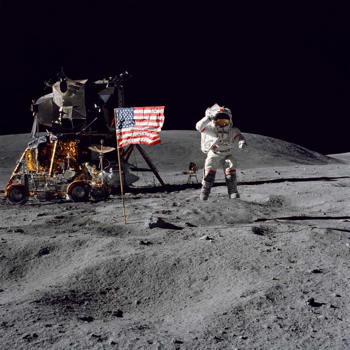Bár a játékfilmekből azt hihetjük, hogy az űrhajósok első dolga volt a holdraszállás után felállítani az amerikai zászlót és felvételeket készíteni vele, ez nem igaz. Első lépésként a holdjárót kellett összeállítani, majd kipakolni a felszerelést és beállítani a mérőeszközöket. Az Amerikai Egyesült Államok zászlajának felállítása valójában az utolsó holdkomp körüli teendő volt. A fotó készültekor John W. Young parancsnok tréfásan felugrott, így lebegve tiszteleg az amerikai zászló előtt. Háttérben balra látható a holdautó, mögötte a holdkomp.
                        
