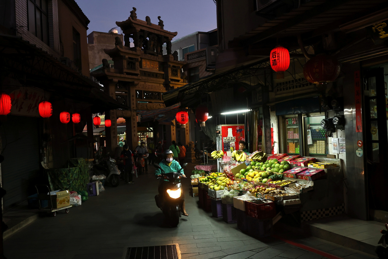 Egy robogó halad el egy gyümölcsárus standja előtt Kinmen egyik régi utcácskájában. Kinmen, 2021. október 17.