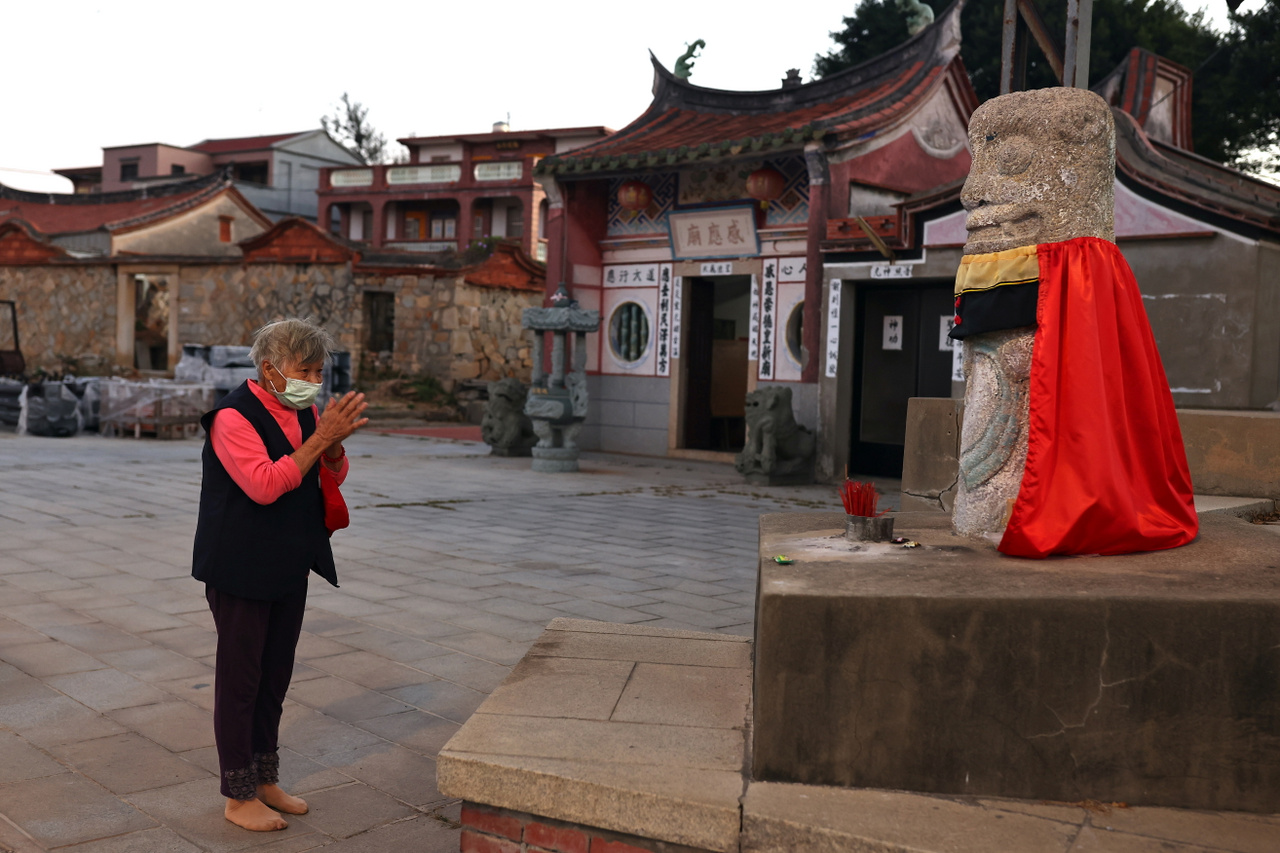 Egy nő imádkozik a szél oroszlán szobrához Kinmen Sanhou falujának templománál. Kinmen, 2021. október 19.