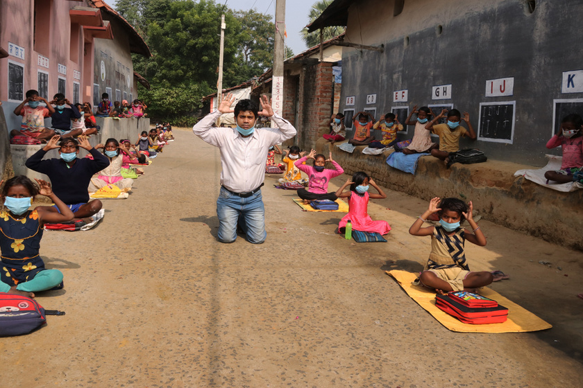 A házak oldalára fest táblákat a tanár, mert bezárt az iskola: az utcán tart órákat az indiai szegény gyerekeknek