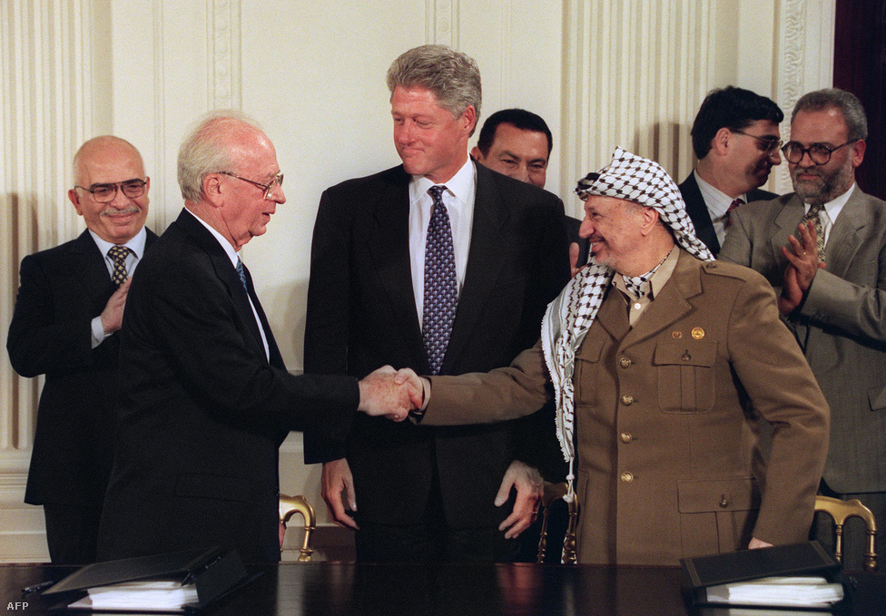 Bill Clinton amerikai elnök közvetítésével kezet fog a hónapokkal később meggyilkolt Jichak Rabin izraeli miniszterelnök és Jasszer Arafat, a PFSZ elnöke 1995. szeptember 28-án a Fehér Házban. A háttérben Hoszni Mubarak egyiptomi elnök és Husszein jordán király figyel. Az 1993-ban aláírt oslói jegyzőkönyvben döntöttek többek között a Palesztin Hatóság felállításáról.