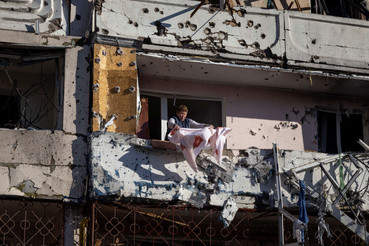 Egy lakó takarítja az erkélyét egy megsérült lakóépületben 2022. március 15-én