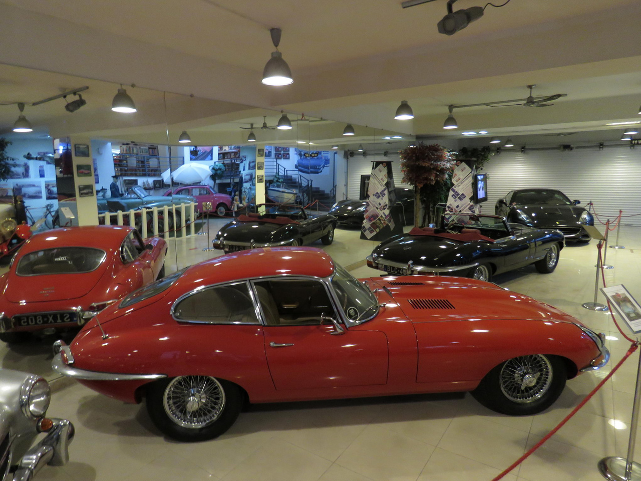 Két Jaguar E-Type egy ilyen kis múzeumban (ráadásként a háttérben egy Ferrari, a viszonylag ritka fekete színben) – mindenképpen szép gyűjtői teljesítmény. Az E-Type-okat tartják sokan a legszebb klasszikus angol sportkocsiknak, és vannak olyan elvetemültek is, akik szerint ezek a valaha épített leggyönyörűbb autók, minden toplista tetején. Mostanság a nevükben szereplő E új értelmet kap: több műhely is elektromos autóvá alakítja őket, a veteránautózás erősen vitatott, de gyorsan terjedő új irányzatának keretében. 