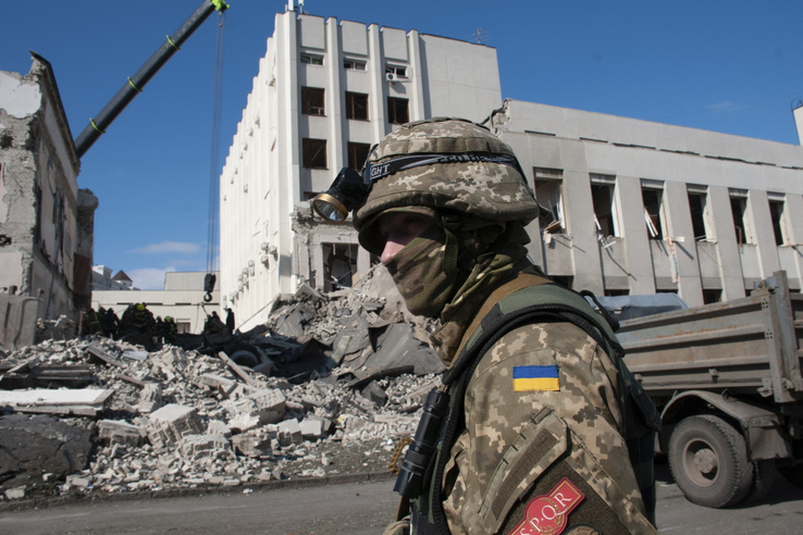 Ukrán katona járőrözik a tüzérségi támadásban megrongálódott nemzeti közigazgatási akadémia romjai mellett Harkivban 2022. március 18-án