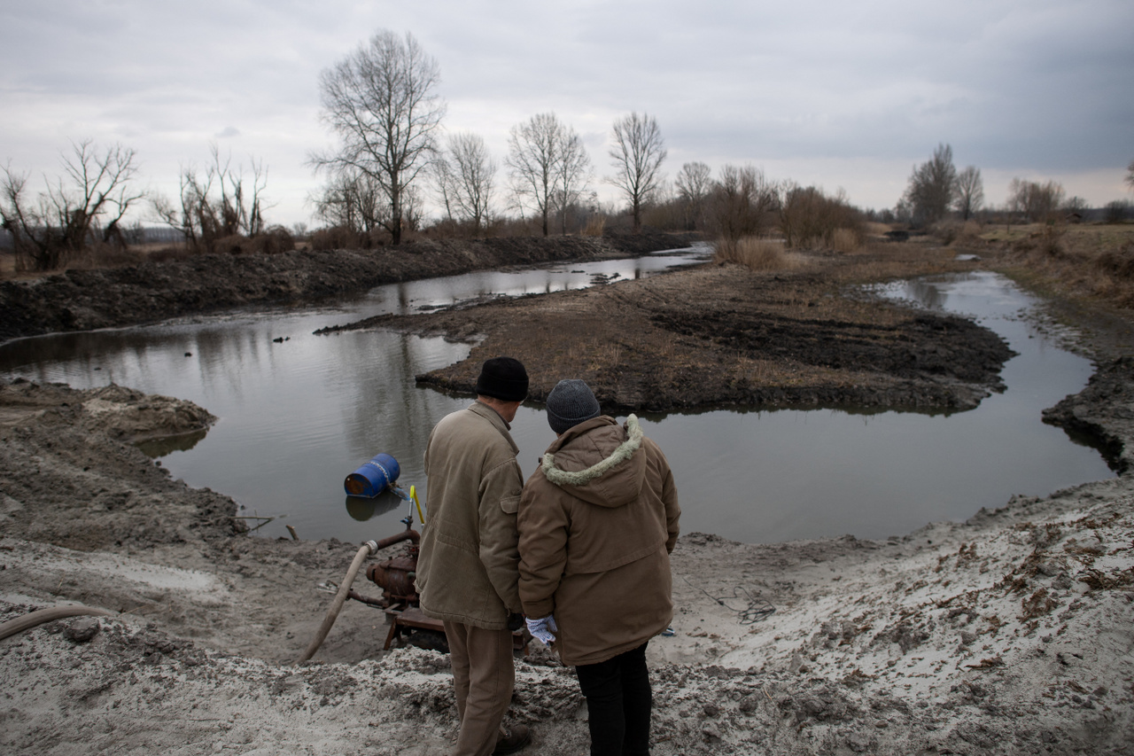 Szepe Ferenc és felesége nézik, amint megpróbálnak talajvizet pumpálva feltölteni egy kiszáradóban lévő tavat Jászszentlászló közelében - 2022. február 1.