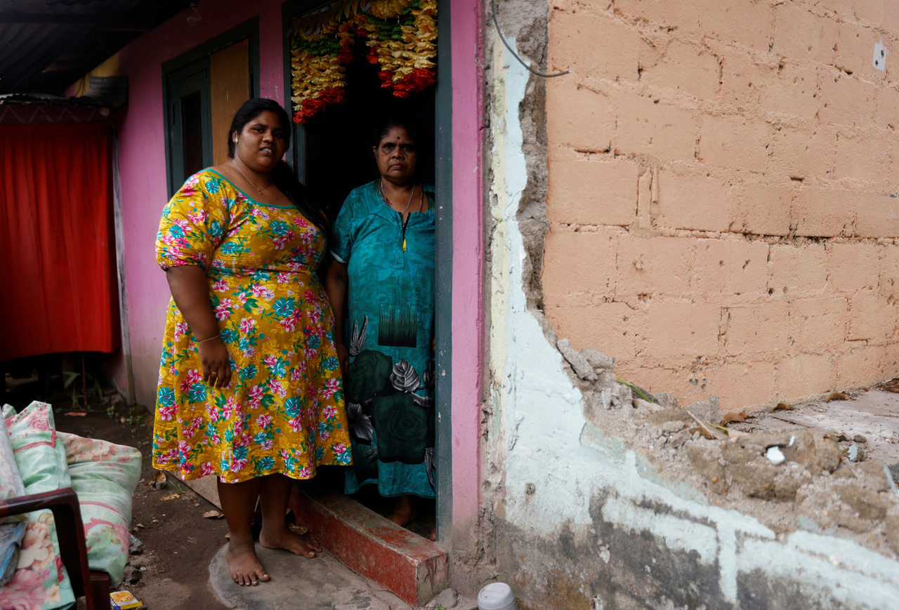 A 29 éves Gayathri áll házuk ajtajában édesanyjával. Mint meséli, régebben naponta háromszor étkeztek, manapság már kihagyják a reggeliket, hogy így spóroljanak. Colombo 2022.08.02.