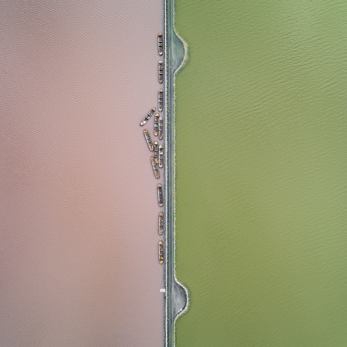Sókitermelő tavak
                        Mályva és zöldre színezett tavakat keresztez az a sínrendszer, amely munkaidőben fém csónakokat húz a tó közepéből a partra, ahol a kitermelt sót feldolgozzák.
                        Torrevieja, Alicante, Spanyolország, 2019