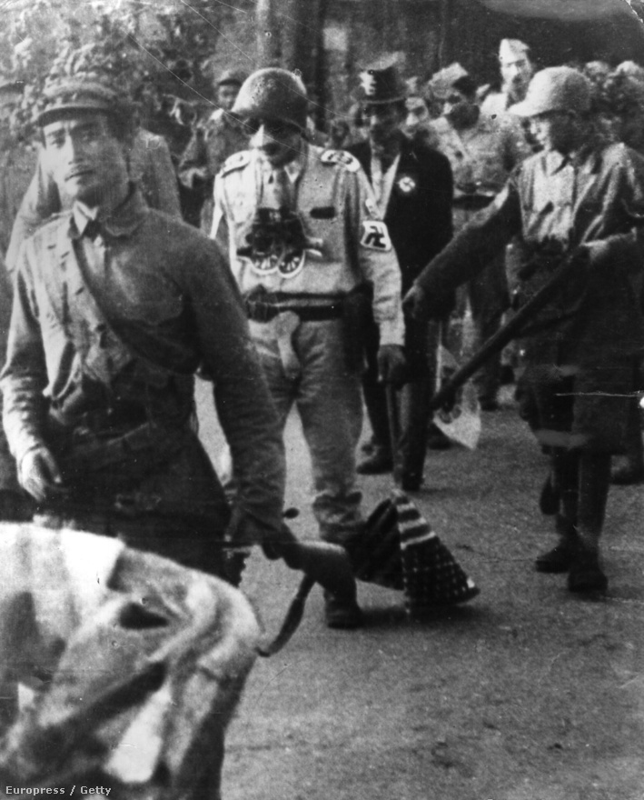 Amerikai hadifoglyok nyilvános megszégyenítése Phenjanban, a képen látható katonának Hitler-bajuszt és horogkeresztes karszalagot viselve, az amerikai zászlót a földön húzva kell végigvonulnia a rajta gúnyolódó északiak között.