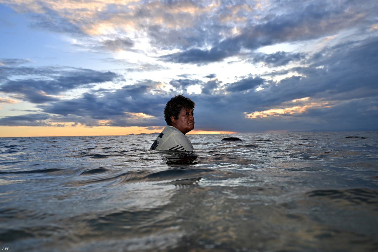 Egy nő úszik naplementekor a főváros, Suva közelében az óceánban. 