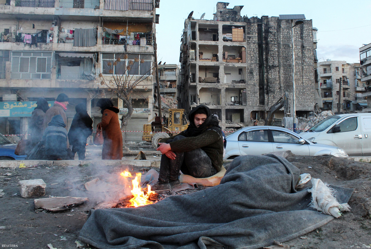Egy férfi melegszik az utcán, miután kimentette otthonából személyes tárgyait a szíriai Aleppóban február 8-án.