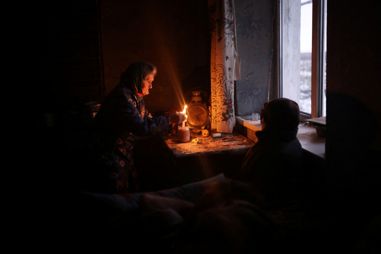 Egyetlen szobájukban gyertya mellett beszélget Volodimir Kovaljov, felesége és unokájuk. 2023. január 30-án.