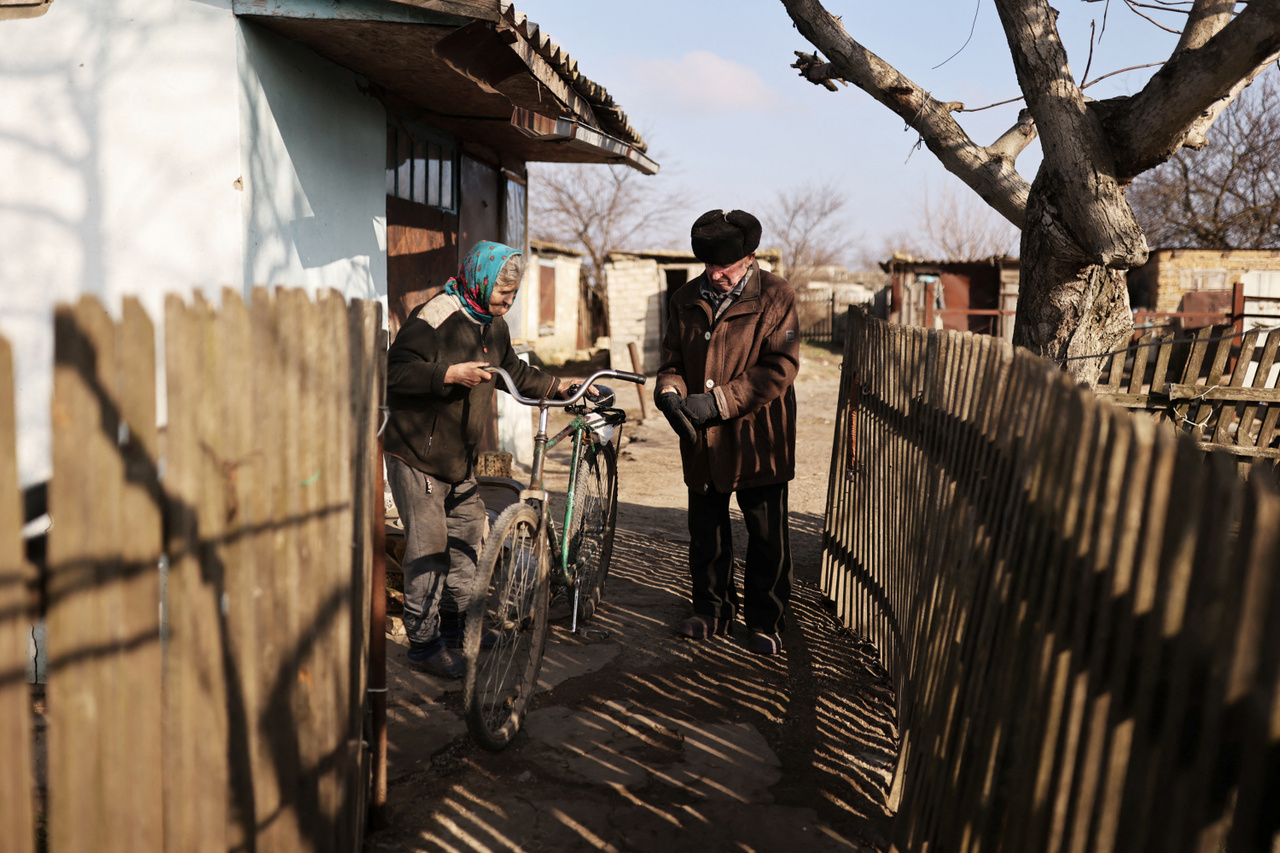 Sztyepan bicikliját tartja felesége, mielőtt elkerekezne a helyi boltba, hogy kiderítse, érkezett-e valamilyen élelmiszer falujukba, amely az orosz-ukrán front közé ékelődött. 2023. január 26-án.