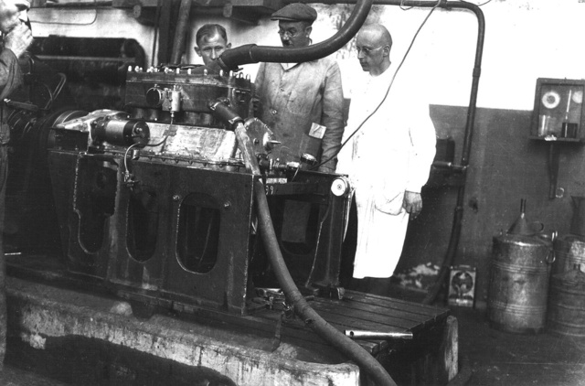 Az első hathengeres motor a fékpadon 1926-ban. Jobbra, fehér köpenyben egy német mérnök, 
                        akit a motor fejlesztésére szerződtettek (Fotó: Collection Burányi)