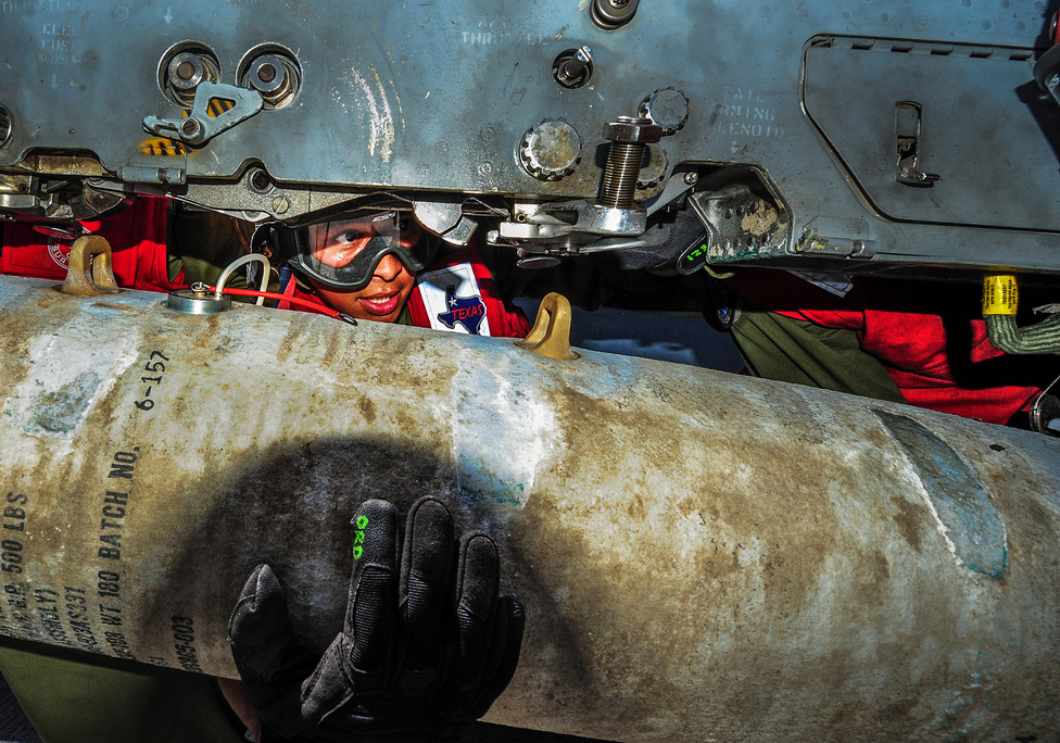 Tony Hernandez őrvezető a USS Boxer fedélzetén, ahogy épp egy siklóbombát erősít egy AV-8B Harrier repülőgépre 2013. augusztus másodikán. A Boxer és személyzete épp a hadrendbe állítás előtti utolsó teszteket végezte a kép készítésekor, hogy bizonyítsa alkalmasságát a bevetés közben várható helyzetekben.