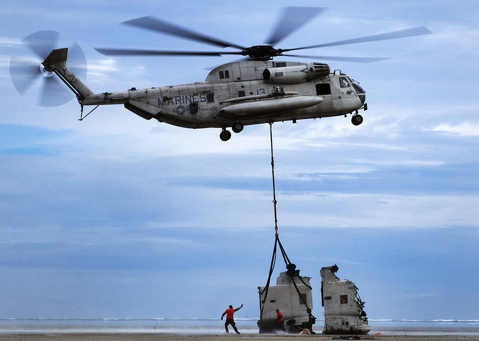 Egy korábban lezuhant helikopter darabjait szállítják el a Hawaii-szigeteki Kaneohe Bayről. A képen egy CH-53D Sea Stallion emeli fel egy másik CH-53D darabját. A szerencsétlenül járt gép 2013. március 29-én zuhant le, a személyzet négy tagjából egy meghalt, három megsebesült.