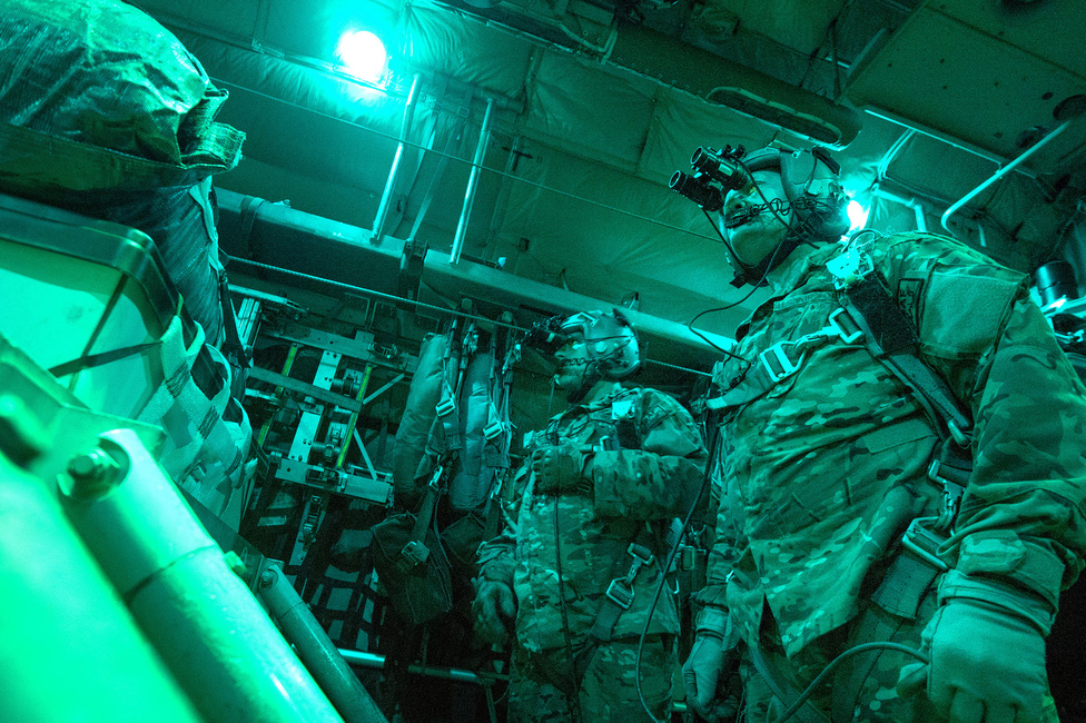 Larry Webster és Richard Mulhollen, a 774-es Légi Szállítási Repülőszázad tisztjei az USA egyik C-130H típusú gépének rakterében várják az engedélyt arra, hogy a nyitott raktérajtón át kidobják a gép ejtőernyővel szerelt rakományát. A kép 2013. október 7-én készült, valahol az afganisztáni légtérben, Ghazni tartomány felett.