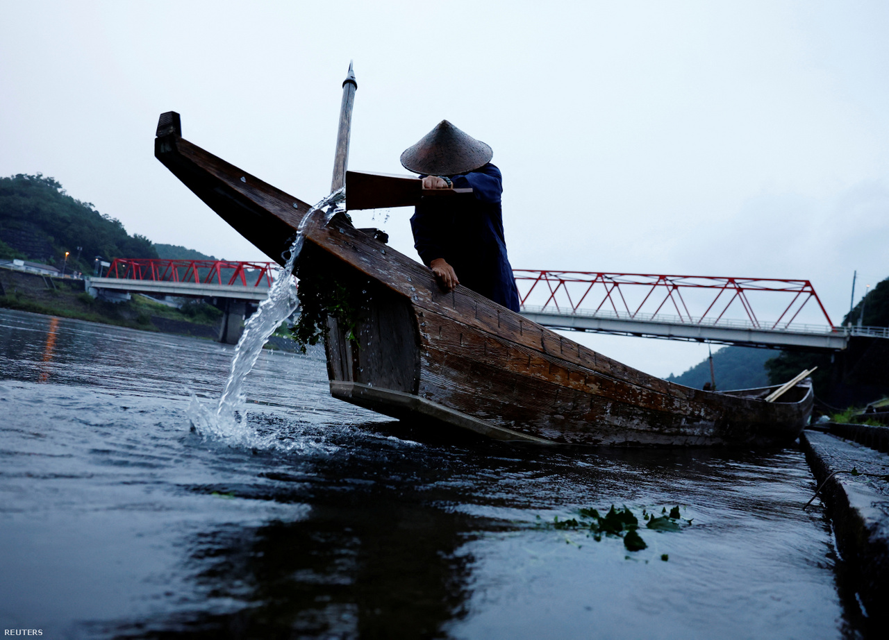 A kormányos meri ki a kormoránhalász csónakból az éjszakai eső után a vizet a Nagara folyón. Oze város, Japán. 2023. szeptember 8.