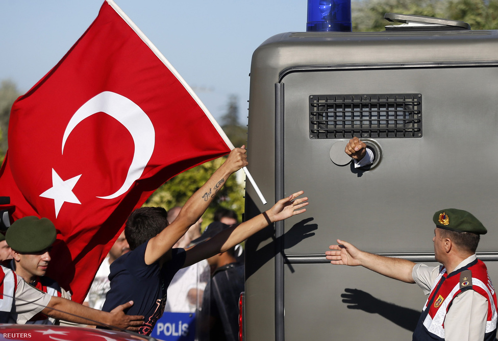 Tüntetők rohannak zászlóval egy rabszállító mögött Törökországban. Augusztusban kezdődtek el a meghallgatások annak a közel háromszáz embernek az ügyében, akiket azzal vádolnak, hogy a kormány megbuktatását tervezték.