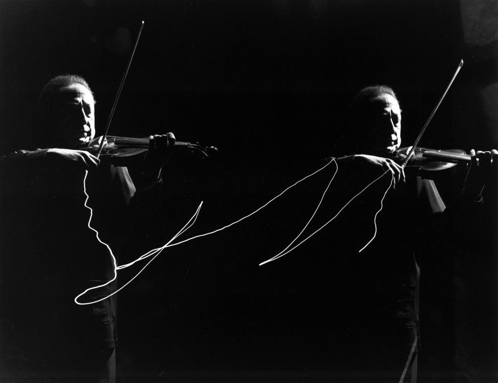Hogyan fényképeznéd le a zenét? Mili ezt is megoldotta: Jashca Heifetz hegedűs vonójára szerelte a kis fényforrást, így tudta megörökíteni a vonó mozgását, miközben egy szép dupla portré is készült a hegedűművészről. 