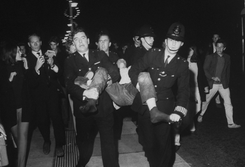 1964, Anglia. Az 1960-as évek nagy ifjúsági összecsapása volt a Mods vs Rockers ellentét, amit a média jól fel tudott fújni. A két csoport véres összetűzései általában rendőri beavatkozást igényeltek, a képen éppen egy rockert tartóztatnak le. 