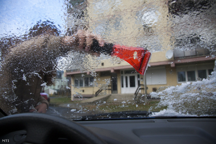 Egy autó ónos esőtõl eljegesedett szélvédőjét tisztítják Nagykanizsán 2016. december 14-én