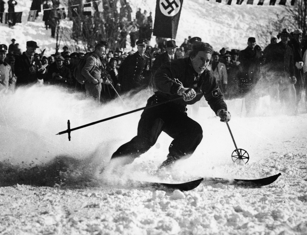 Kezdetben a Nemzetközi Olimpiai Bizottság törekvése az volt, hogy ugyanaz az ország rendezze a téli és a nyári olimpiát is. 1936-ban ez azonban nem sült el túl jól, Hitler mindkét eseményt, a berlini és a garmisch-partenkircheni olimpiát a náci propaganda céljaira használta fel. A horogkeresztes zászló előtt a tizenkétszeres világbajnok Christl Cranz síel el. Cranz 1936-ben a kombináció világbajnoka lett.