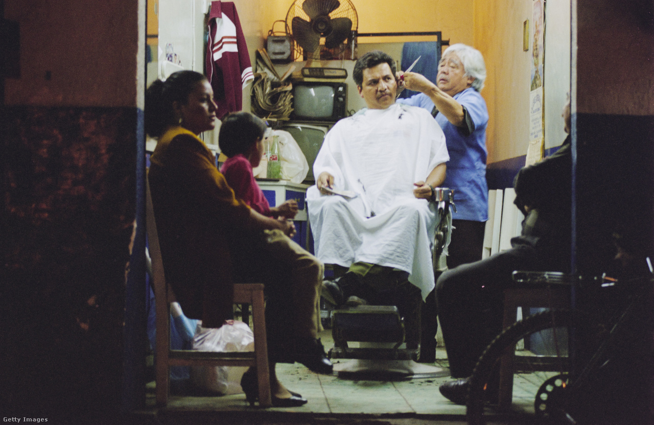 Mexikó és Kalifornia határa, Egyesült Államok,1993. Egy nő és gyermeke vár, amíg egy mexikói férfi haját vágja a fodrász