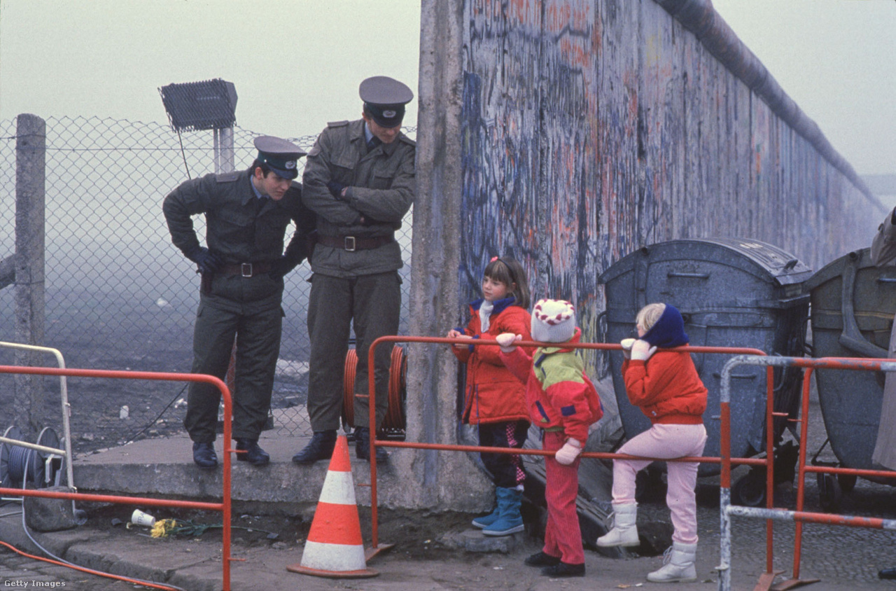 Berlin, Németország, 1989. november 14. Nyugat-német gyerekek az iskolába menet átnéznek a megnyitott berlini falon, amelynél két kelet-német határőr áll