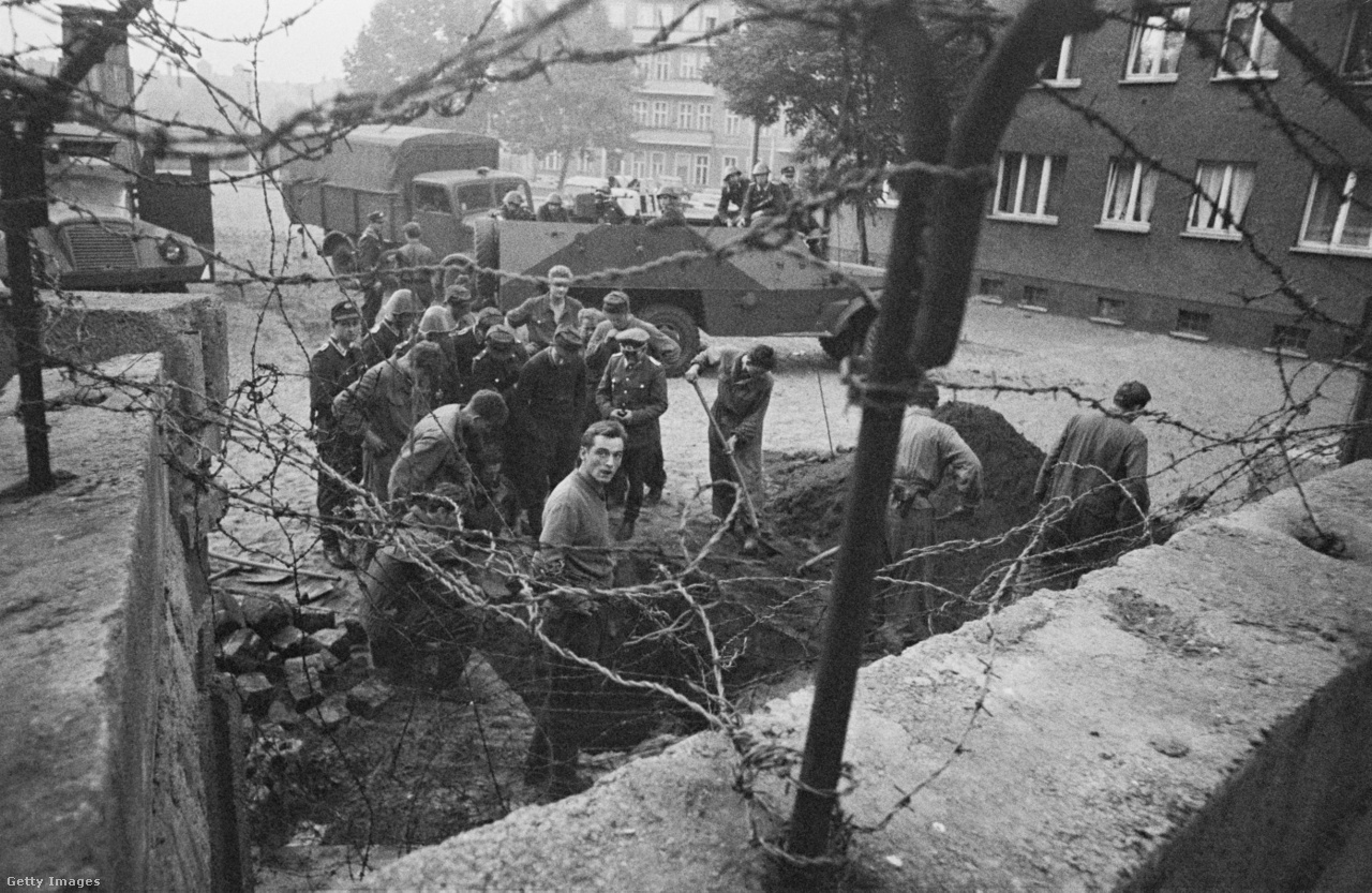Berlin, Németország, 1962. október. Kelet-német őrök vizsgálnak egy nagy lyukat vagy alagutat a Harzer Strassén a berlini fal mellett