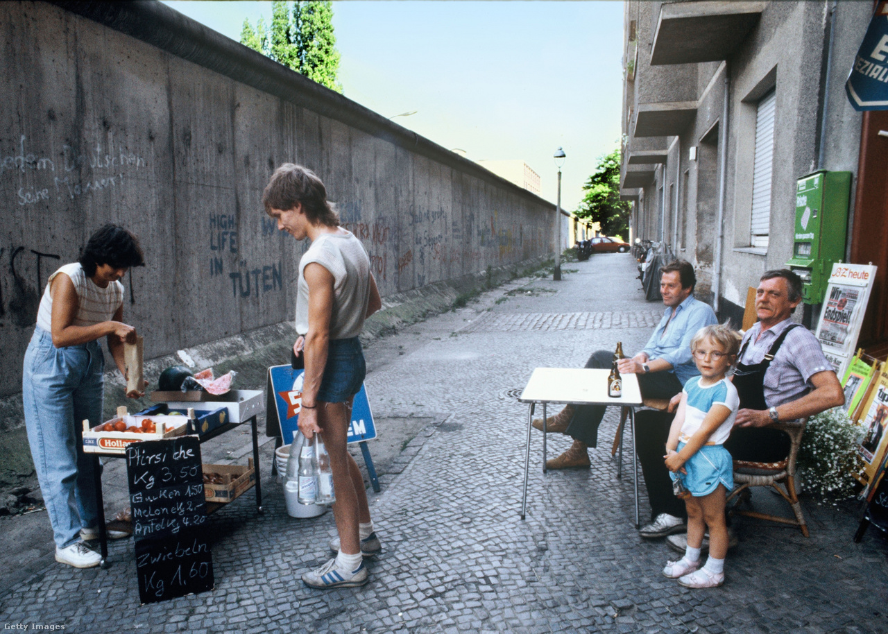 Zimmerstrasse, Kreuzberg, Berlin, Németország, 1986 július. A pár hónappal később 25 éves berlini fal része a lakosok mindennapi életének, az árnyékában lehet lazítani egy kicsit, egy sört meginni munka után, míg egy kis családi kioszk árusít a labdarúgó világbajnokság alatt