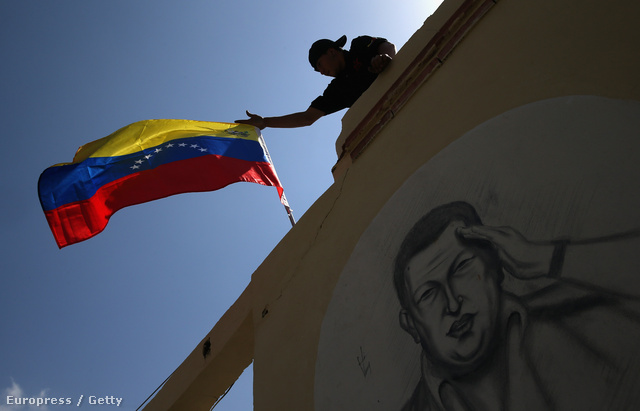Chávez egyik híve zászlót tűz egy a volt elnök képével díszített falra, a "Comandante Supremo" sírja közelében.