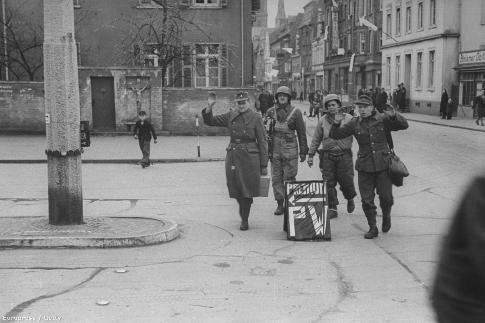 Két német hadifogolyt kísérnek amerikaiak egy háborús börtönbe Berlin utcáin.