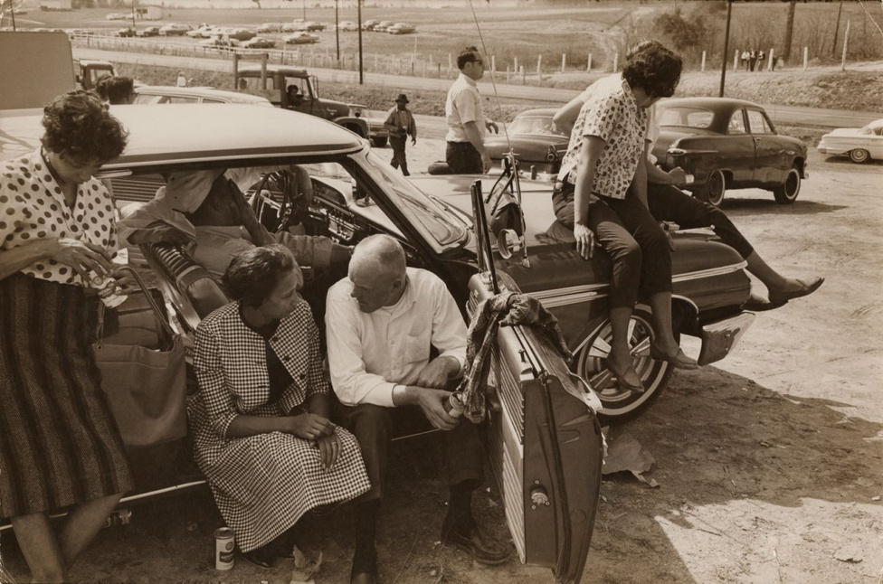Richard és Mildred üldögélnek az autójukban. Richard amatőr autóversenyző volt, itt éppen megnyert egy versenyt. 
                        