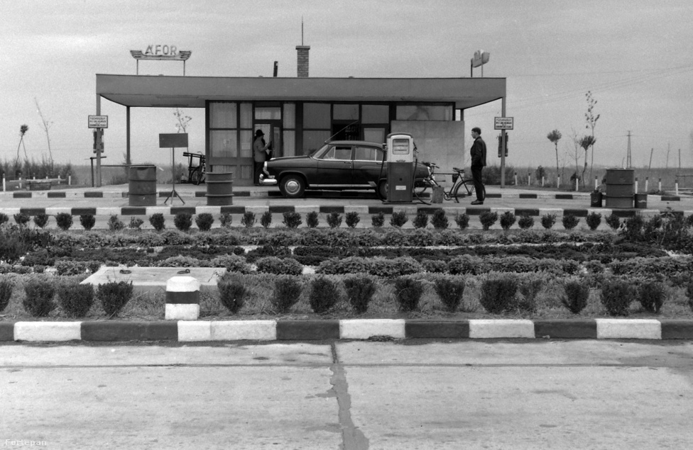 
                        A nagy balatoni út előtt mindig érdemes volt még Budaörs vagy Diósd környékén feltankolni egy olyan tipikus ÁFOR-kútnál, mint ami a fenti képen is látható, hogy ne legyen gond később a benzinnel. A fotó egyébként 1970-es, és az állami benzinkút mellett a régi balatoni műút jellegzetes rázós aszfaltkockáit is gyönyörűen megörökítette. A műút fővárosi szakaszát már 1937 nyarán átadta az utazóközönségnek Dr. Szendy Károly, Budapest akkori polgármestere &ndash; az eseményről természetesen a kor divatja szerint filmhíradó is készült. A Balatonhoz való eljutást megkönnyítő M7-es viszont jóval később készült el, és csak 1975-re kötötte össze Balatonaligát Budapesttel.
                        